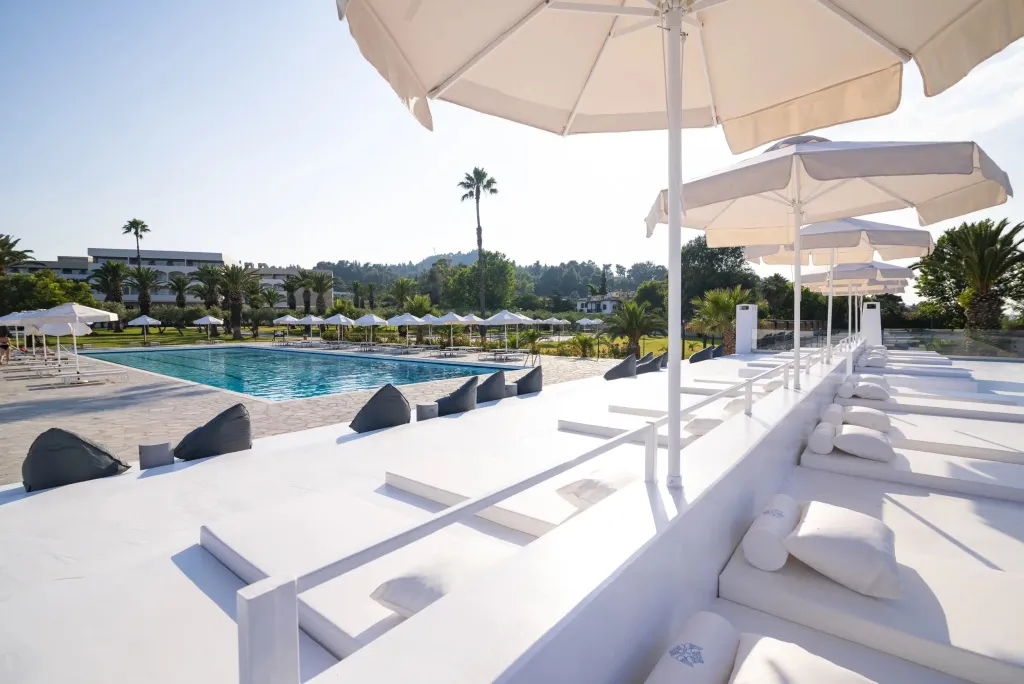 Transats blancs alignés au bord d'une piscine ensoleillée.