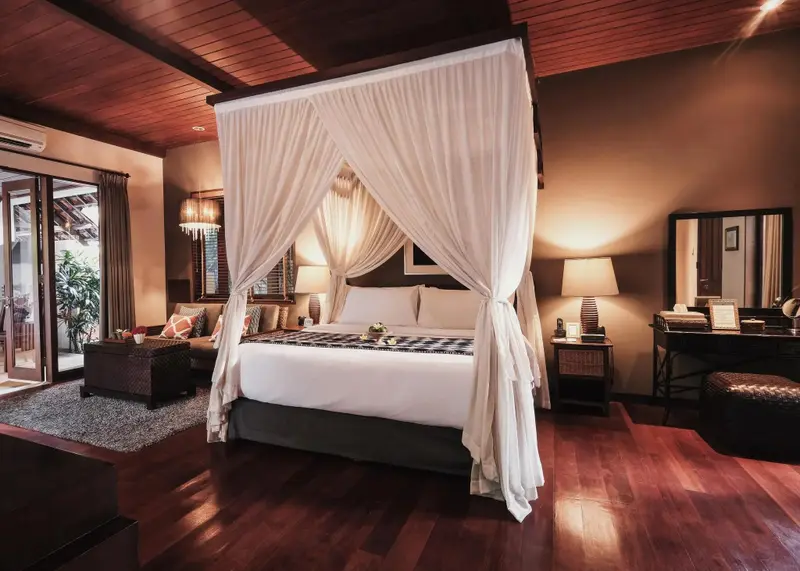 Une chambre spacieuse avec un lit à baldaquin et un coin salon.