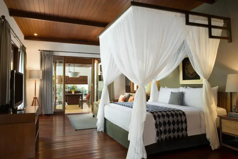 Une chambre spacieuse avec un grand lit à baldaquin et un accès à une terrasse.