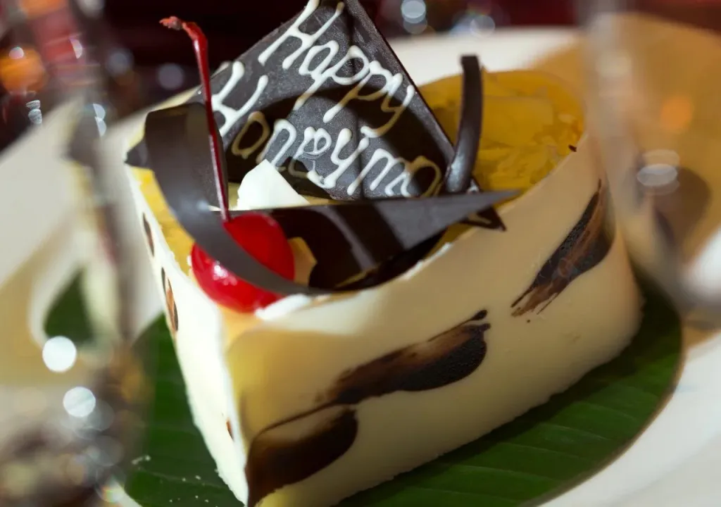 Un dessert à la crème décoré d'une cerise et d'un message en chocolat.