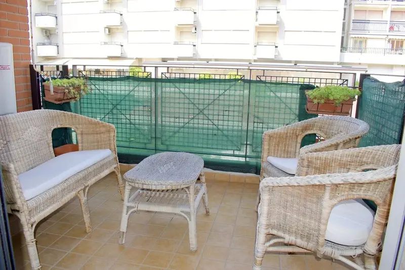 Un espace extérieur aménagé avec des meubles en rotin et des jardinières fleuries.