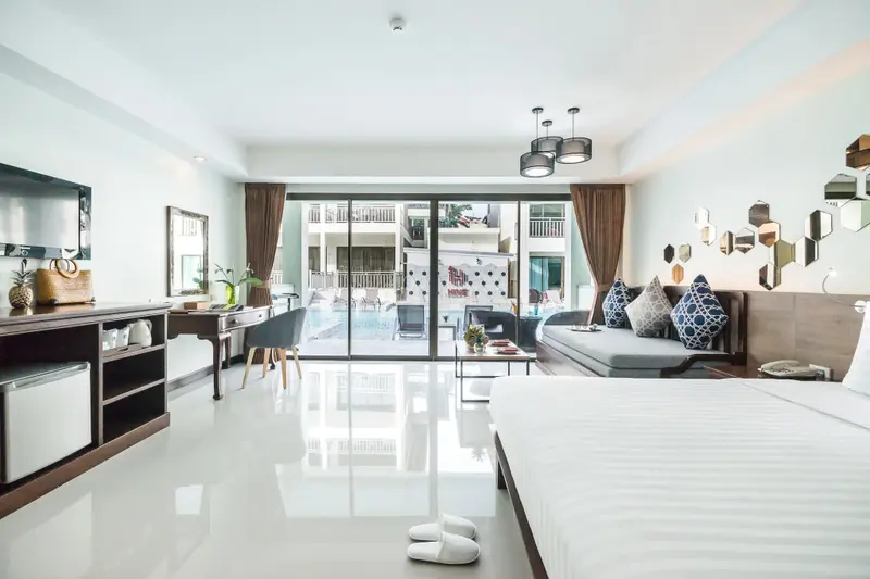 Une chambre lumineuse s'ouvre sur une piscine par de grandes baies vitrées.