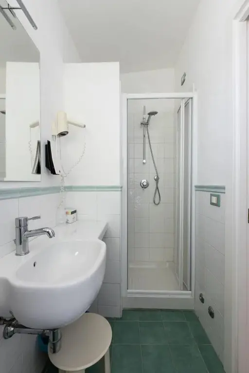 Une salle de bain claire avec douche et lavabo.