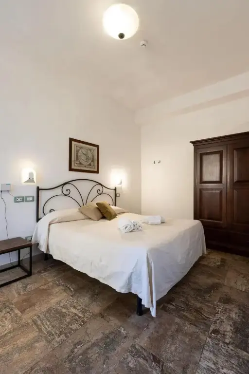 Une chambre lumineuse avec un grand lit recouvert de draps blancs et un placard en bois.