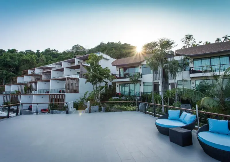 Terrasse spacieuse avec mobilier d'extérieur devant des bâtiments blancs.