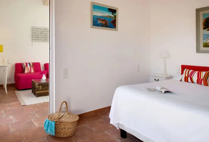 Une chambre lumineuse avec un lit blanc et un coin salon rose.