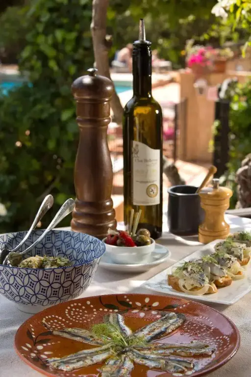 Une table est dressée avec des plats et des boissons dans un cadre extérieur ensoleillé.