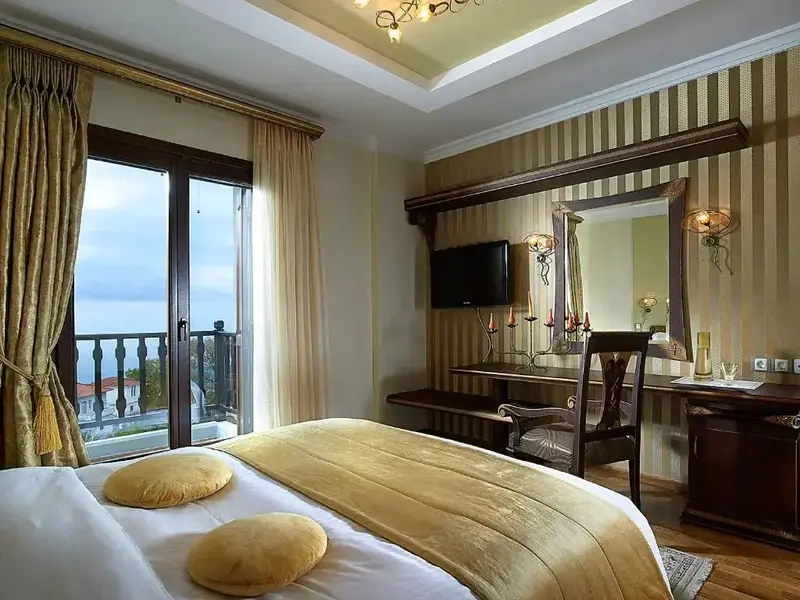Une chambre lumineuse avec un grand lit et un bureau près d'une fenêtre donnant sur un paysage.