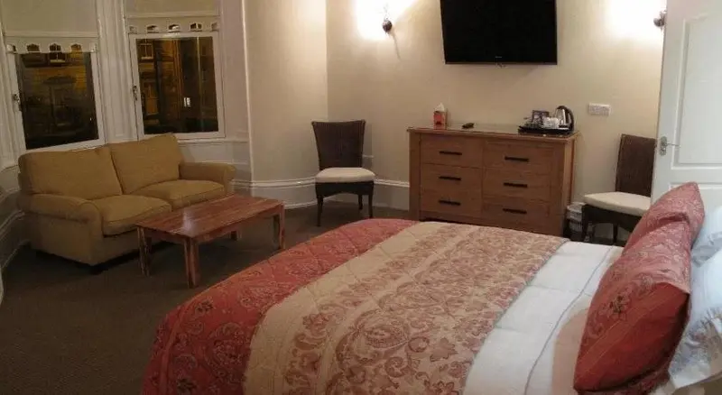 Une chambre lumineuse avec un canapé, un lit et un buffet.