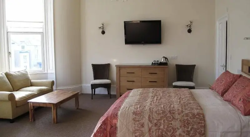 Une chambre lumineuse avec un canapé, une commode et un grand lit.