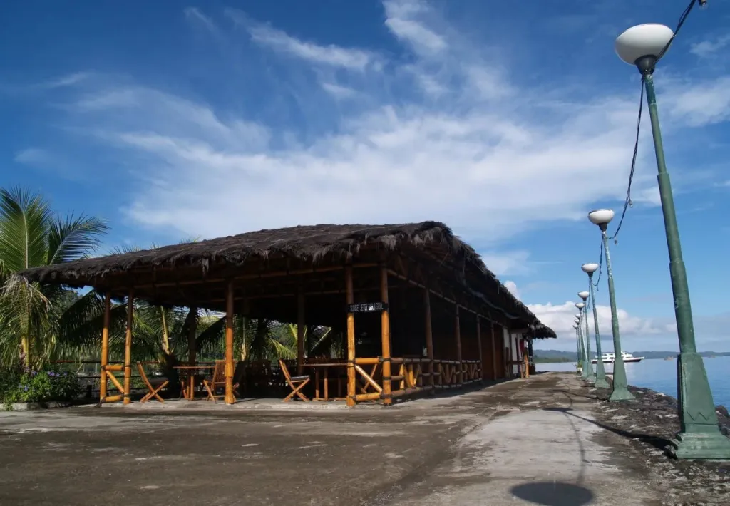 Terrasse ombragée avec mobilier en bois face à la mer.