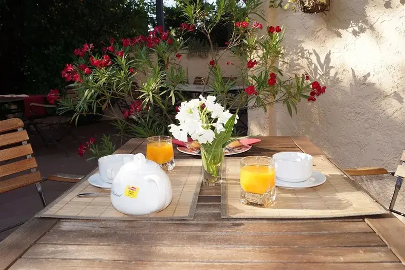 Une table est dressée pour le petit-déjeuner sur une terrasse ensoleillée.