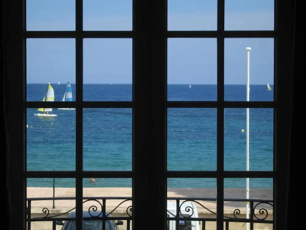 Vue sur la mer depuis une fenêtre avec un cadre sombre.