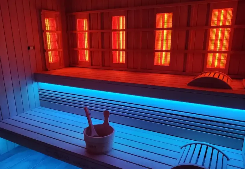 Intérieur d'un sauna en bois éclairé de lumières rouge et bleu.