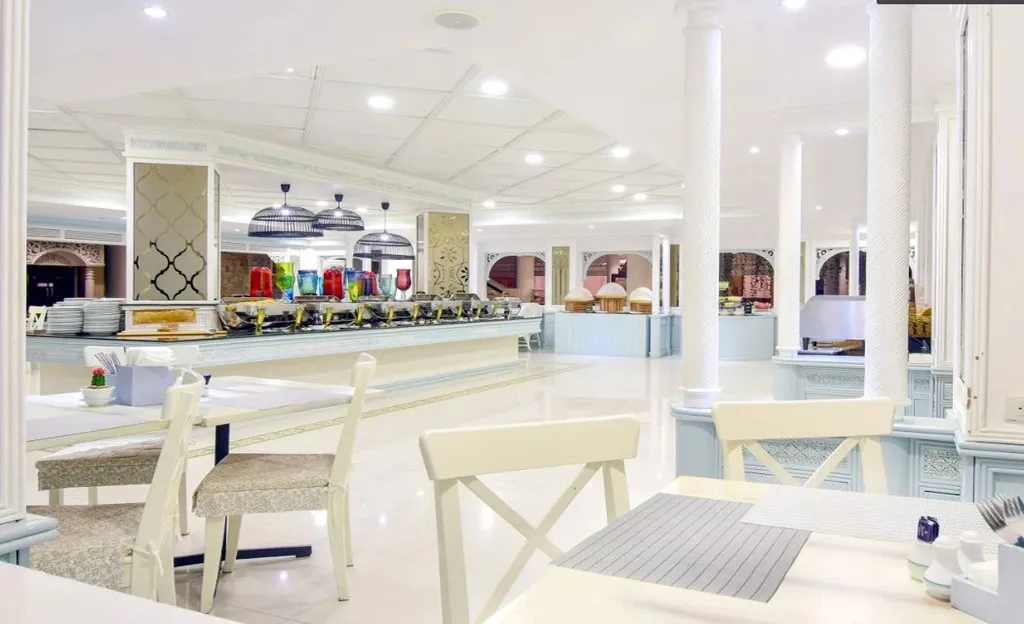 Une salle lumineuse avec un long buffet de nourriture et des tables à manger.