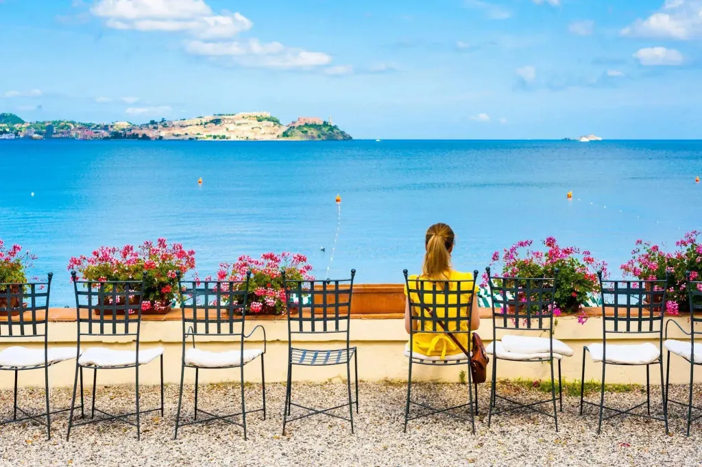 Une personne est assise sur une chaise face à la mer.