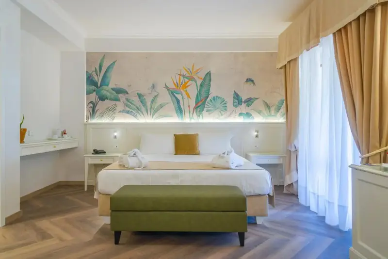 Une chambre lumineuse avec un grand lit et une décoration florale murale.