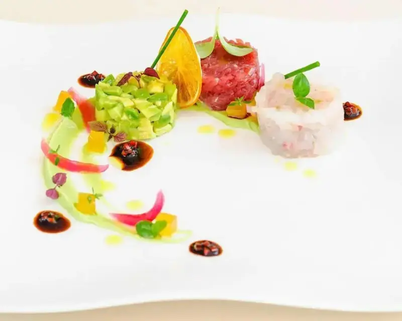 Assiette raffinée composée de tartare de poisson, d'avocat et d'agrumes.