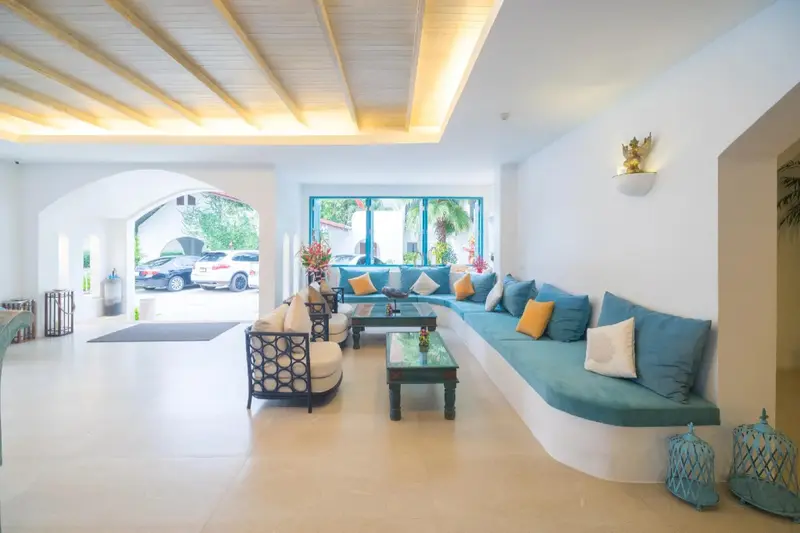 Espace de détente lumineux avec canapés et mobilier en rotin.
