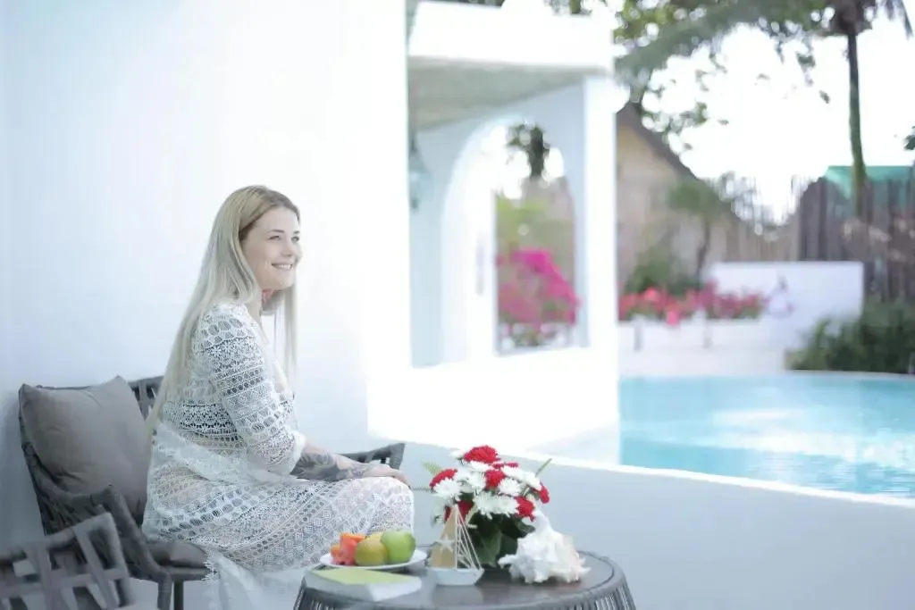 Une femme est assise sur une terrasse près d'une piscine.