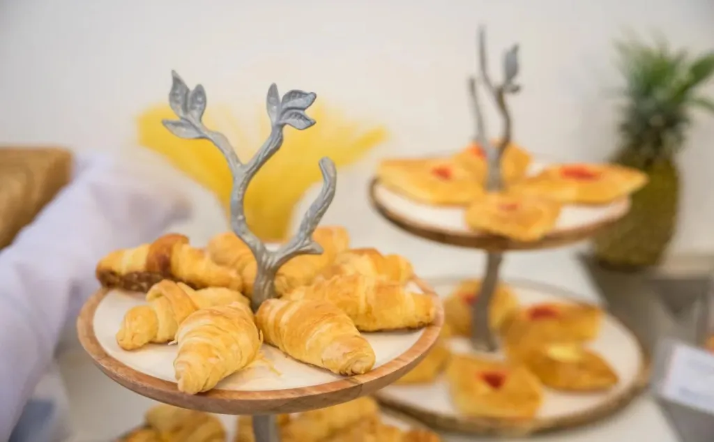 Des viennoiseries et des pâtisseries sont présentées sur des présentoirs à étages.