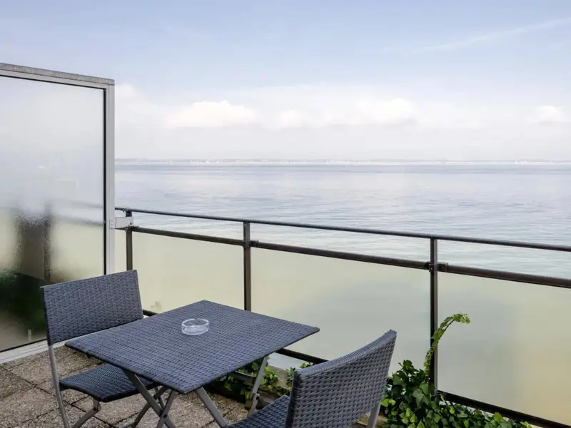 Terrasse avec table et chaises donnant sur la mer.