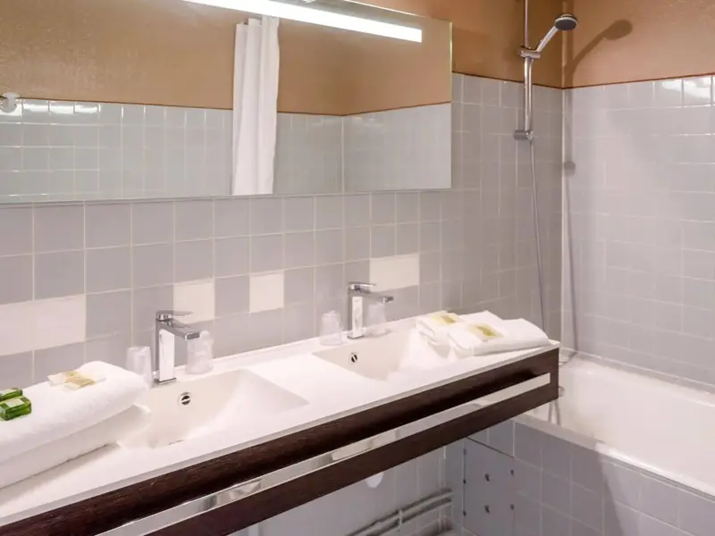 Une salle de bain lumineuse avec deux vasques et une baignoire.