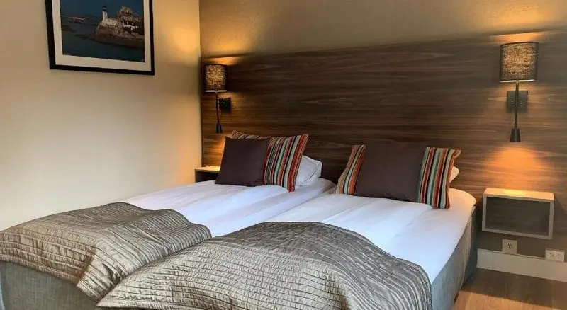 Deux lits simples dans une chambre aux murs clairs et au décor moderne.