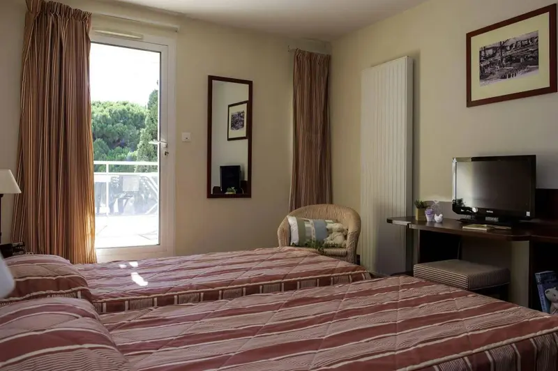 Une chambre lumineuse avec deux lits et une vue sur un espace extérieur.