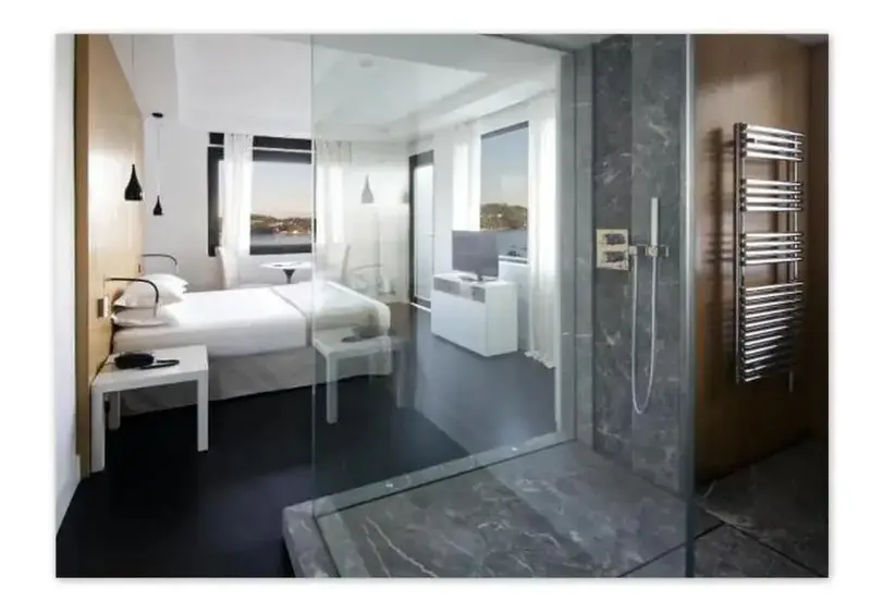 Une chambre moderne avec un lit blanc et une salle de bain ouverte.