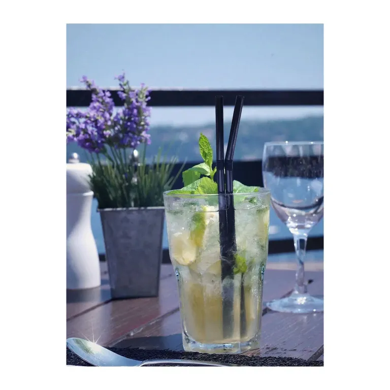 Boissons fraîches et fleurs sur une table en extérieur avec vue sur la mer.