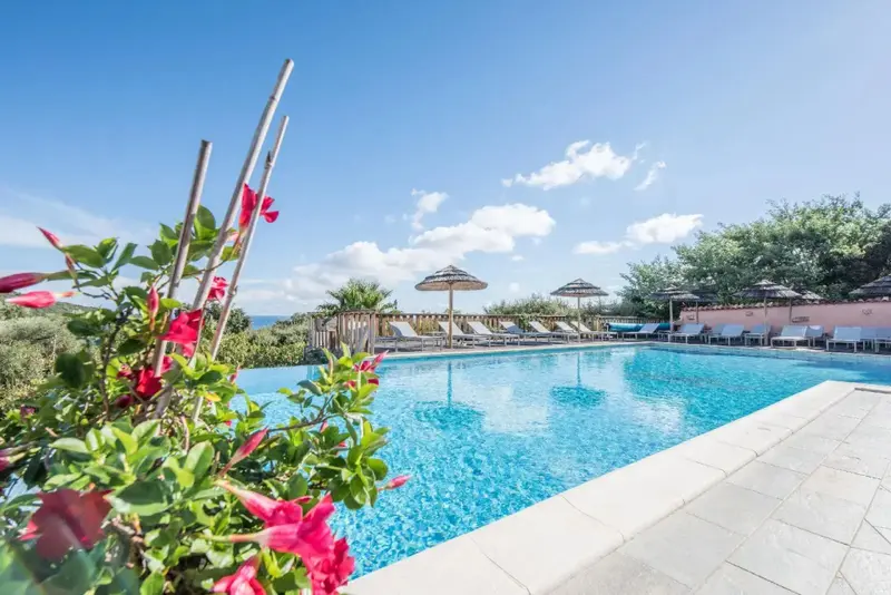 Une piscine rectangulaire bordée d'une terrasse ensoleillée avec des parasols.