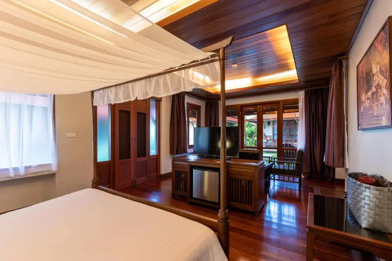 Une chambre spacieuse avec un lit à baldaquin et un meuble télévision.