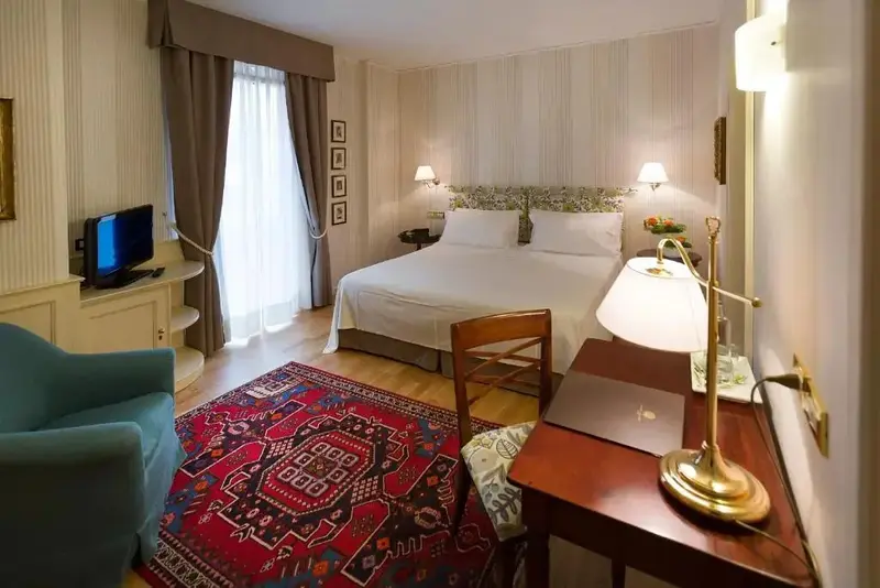 Une chambre lumineuse avec un grand lit et un tapis oriental.