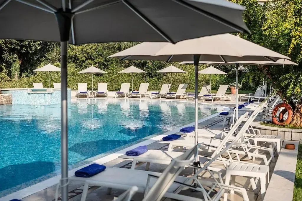 Transats blancs alignés au bord d'une piscine ensoleillée.