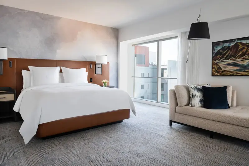 Une chambre lumineuse avec un grand lit et un coin salon près d'une fenêtre.