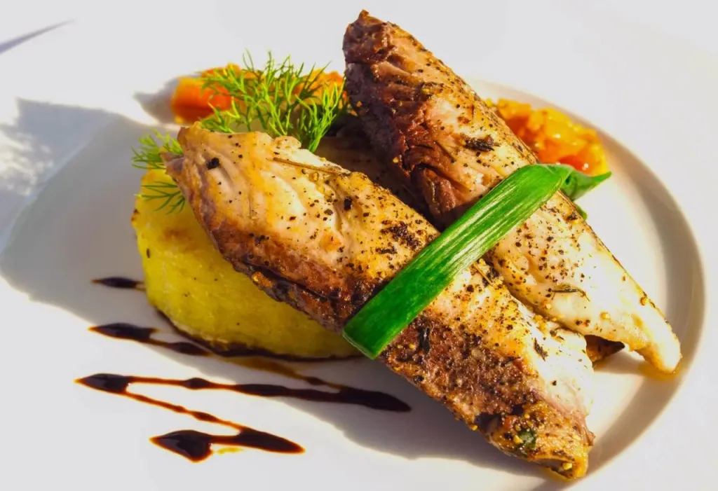 Assiette de poisson grillé accompagnée d'une purée et d'une sauce.
