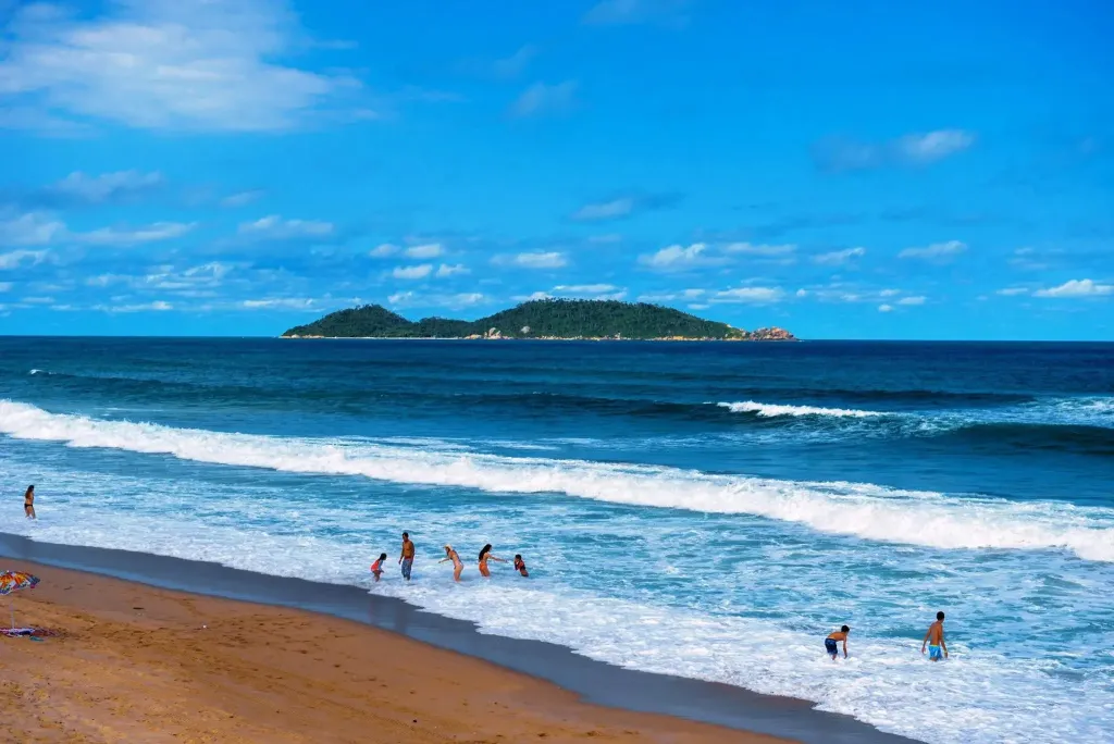 Une plage de sable fin bordée par une mer turquoise et une île verdoyante.
