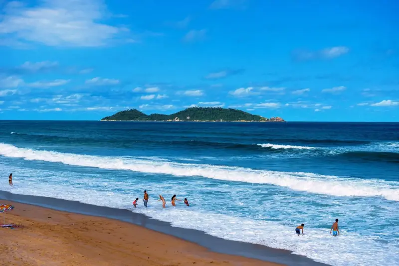 Une plage de sable fin bordée par une mer turquoise et une île verdoyante.