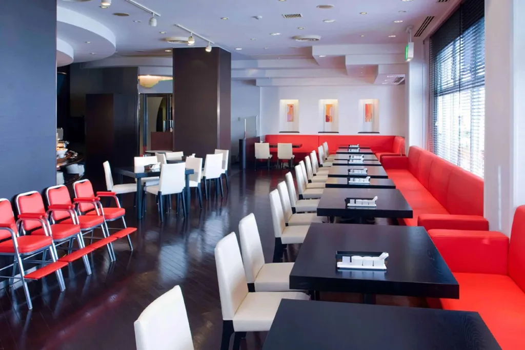 Une salle lumineuse avec des tables et des banquettes rouges et blanches.