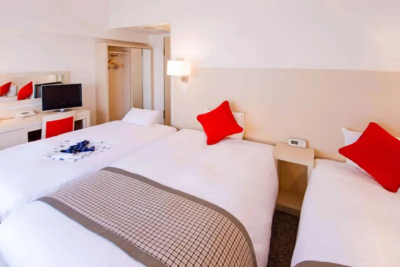 Une chambre d'hôtel lumineuse avec deux lits simples et une télévision.
