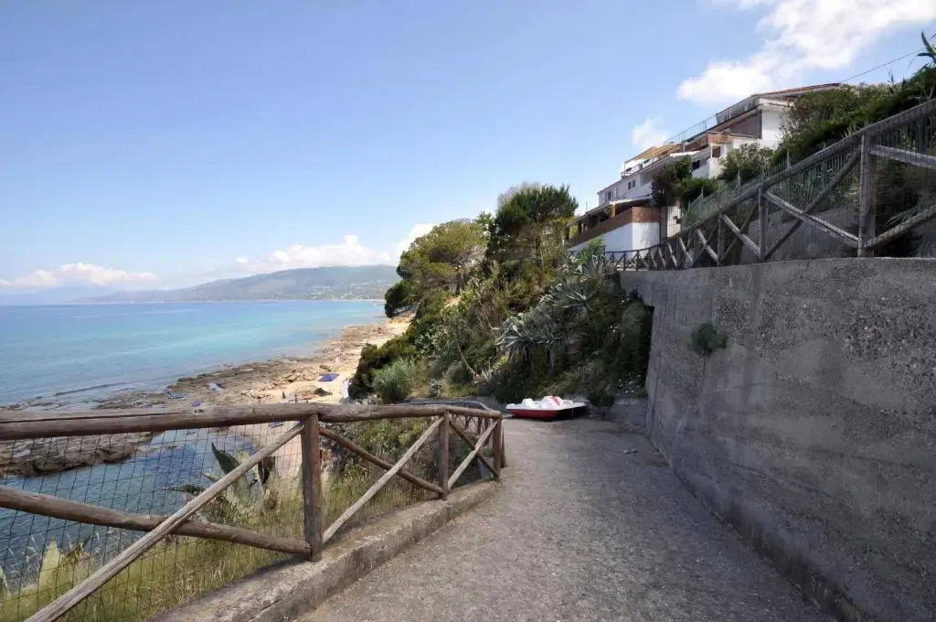 Un chemin descend vers une plage rocheuse en bord de mer.