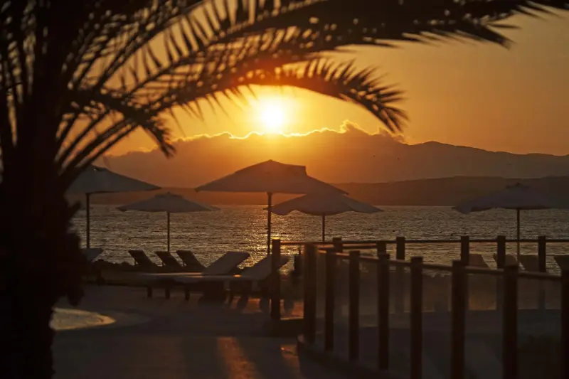 Coucher de soleil sur la mer avec transats et parasols.