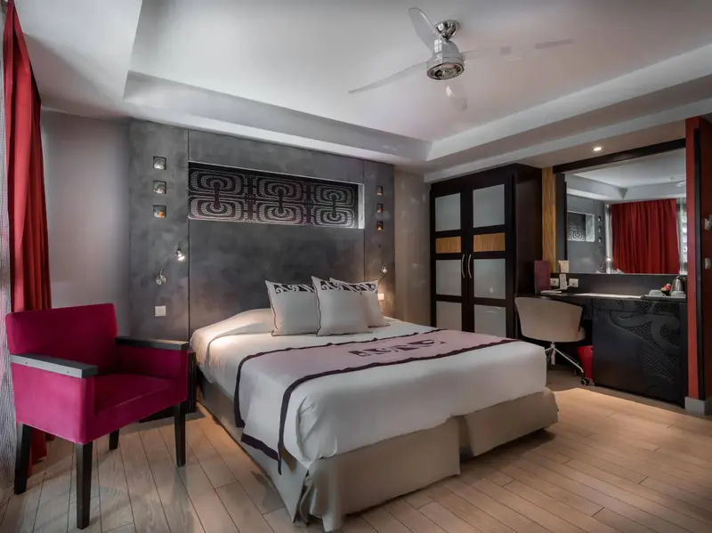 Une chambre moderne avec un grand lit et un fauteuil rose.