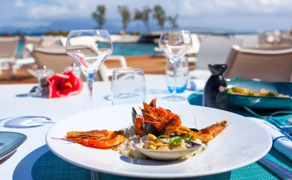 Assiette de fruits de mer présentée sur une table en extérieur avec vue sur la mer.