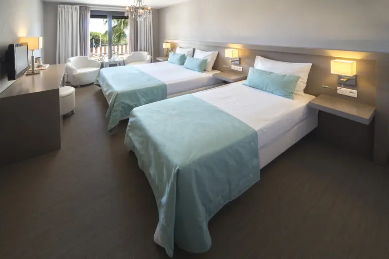 Une chambre lumineuse avec deux lits simples et une décoration sobre.