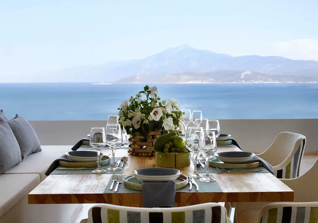 Une table dressée avec une vue sur la mer et les montagnes.