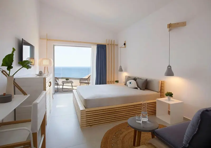Une chambre lumineuse avec un lit et un accès à une terrasse vue sur mer.