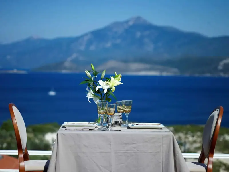 Table dressée pour un repas avec vue sur la mer et les montagnes.