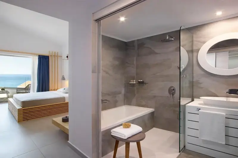 Une chambre lumineuse s'ouvre sur une salle de bain avec douche à l'italienne et baignoire.